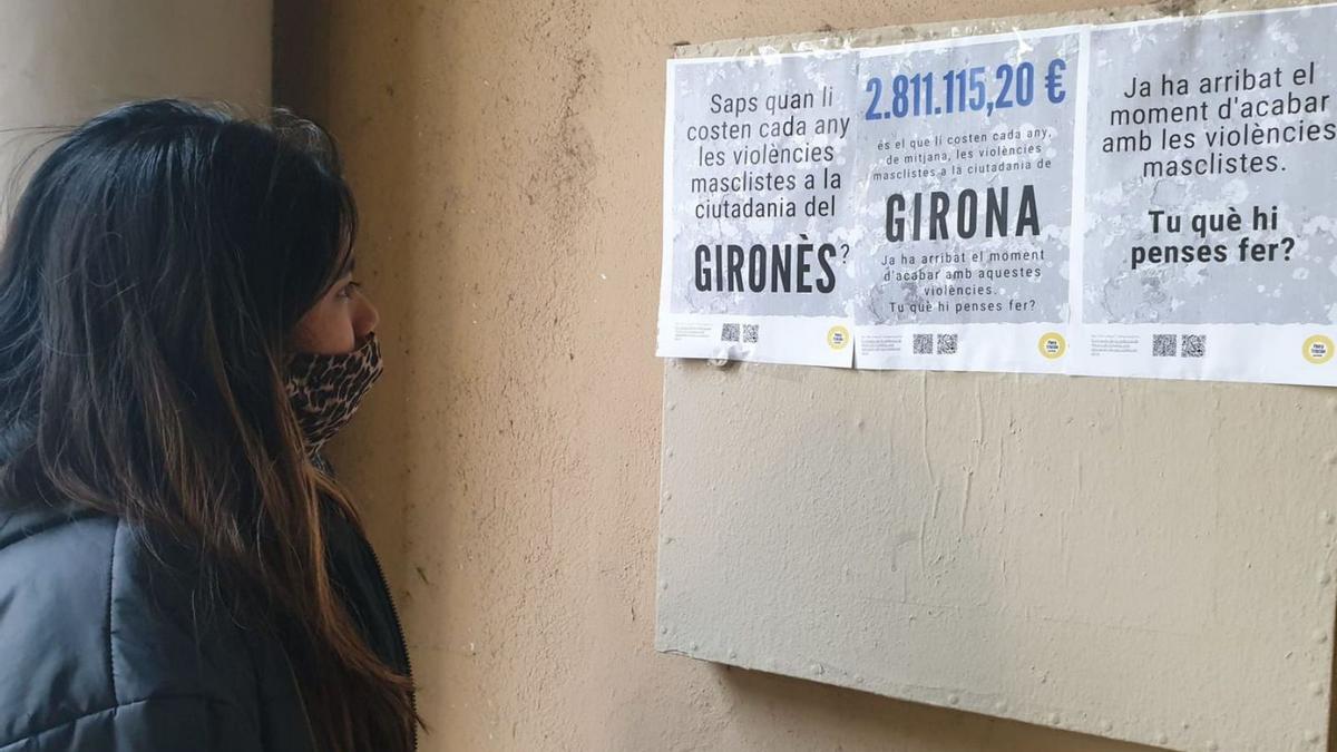 Una jove a Girona mirant els cartells que ha difós el col·lectiu Flora Tristán | ORIOL PUIG