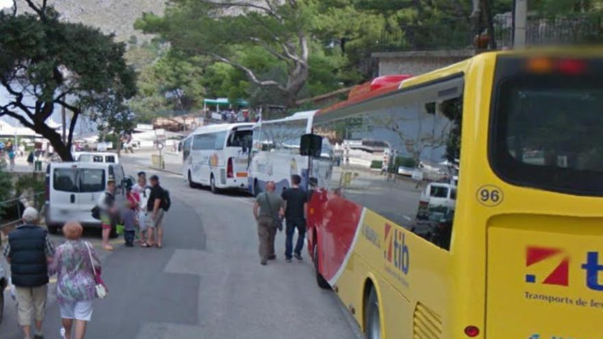 Varios excursionistas deambulan por el acceso principal a sa Colobra ante varios autocares estacionados en el lugar.