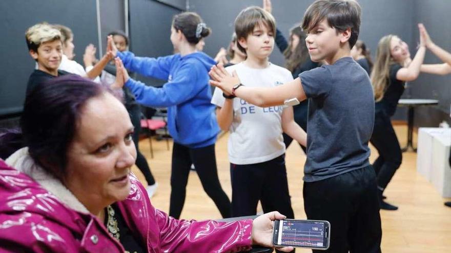 Lydia muestra cómo controla desde el móvil el nivel de glucosa de Pablo (detrás), con el sensor en el brazo, durante su clase de teatro. // J. Lores