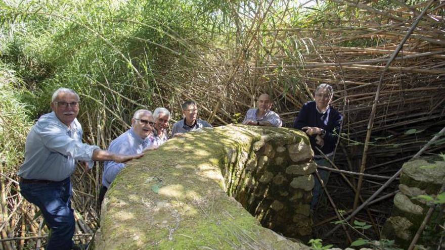 Una familia bebe agua de la antigua fuente. | FAMILIA TRULLENQUE