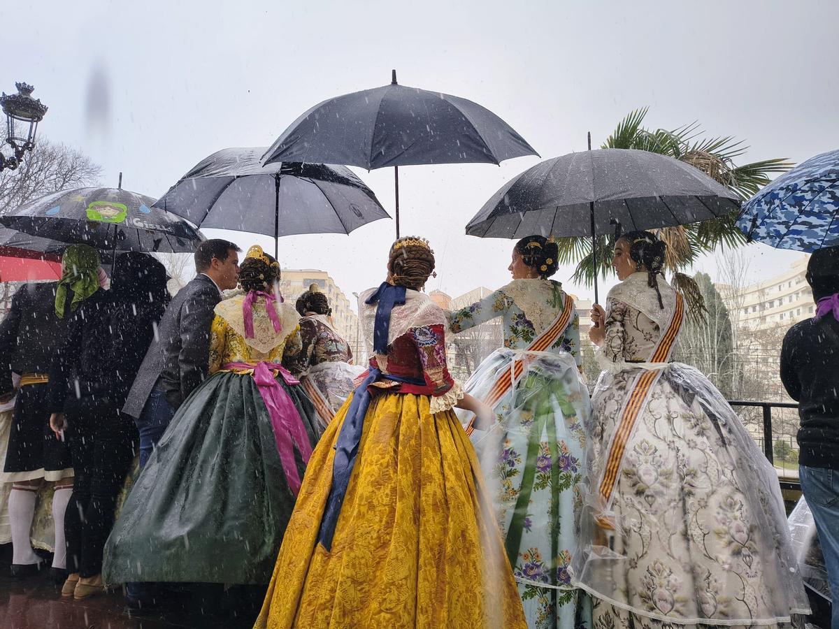 Falleras y autoridades resguardas de la lluvia durante la mascletà que se ha disparado hoy -16 de marzo- en Xàtiva.