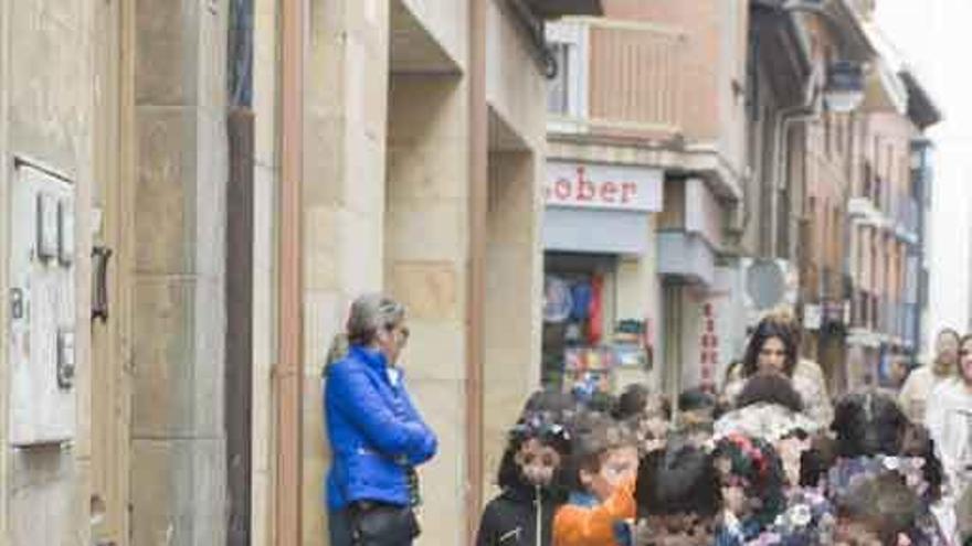 Un grupo de escolares observa a un hombre pidiendo en la calle Herreros.