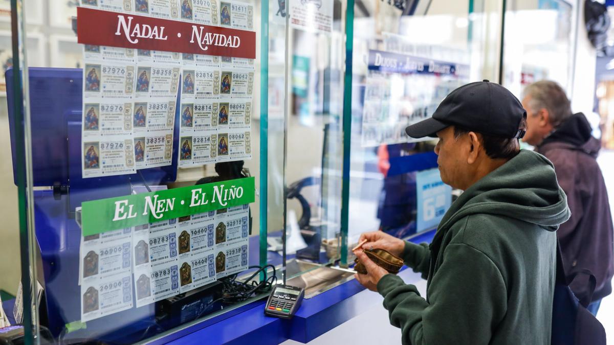 Dos personas comprando décimos de la Lotería de Navidad en la mítica administración El Gato Negro