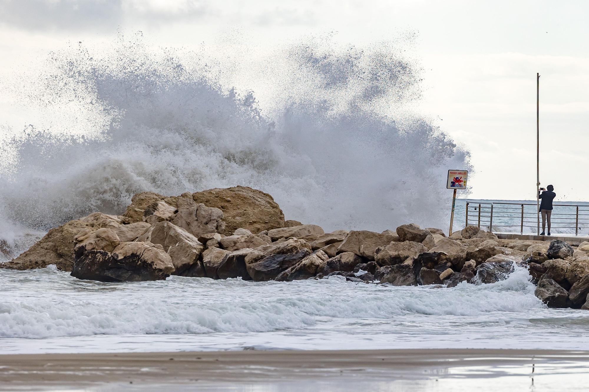 Turistas y paseantes observan el temporal de mar en la Cala de Finestrat