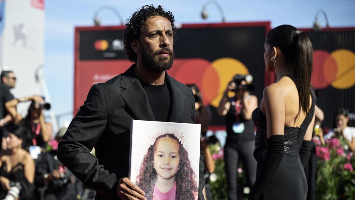 El actor palestino, Motaz Malhees, muestra una foto de Hind Rajab durante el estreno de 'La voz de Hind' en el Festival de Venecia.