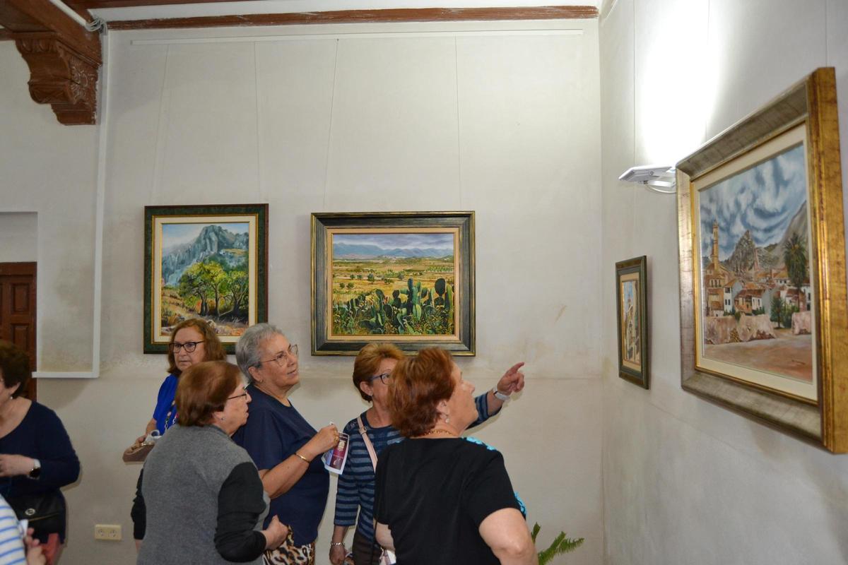 Un grupo e mujeres contempla los cuadros de la muestra pictórica