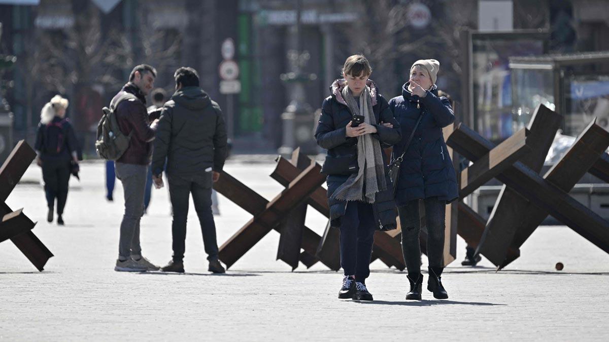 Ciudadanos pasean cerca de obstáculos anti-tanques en el centro de Kiev