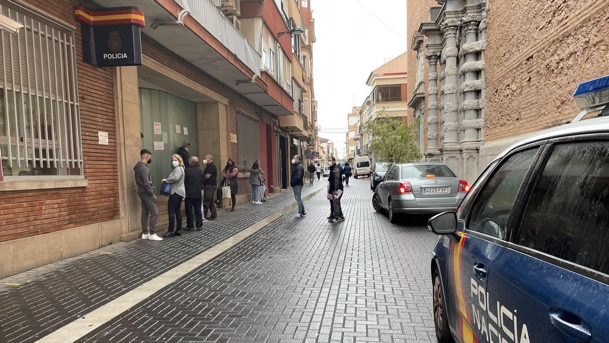 Gente hace cola en la calle, donde también se aparcan varios vehículos policiales, para entrar ayer a la comisaría de la Policía Nacional, en Vila-real.