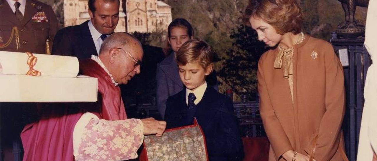 Por la izquierda, el abad de Covadonga, Emiliano de la Huerga, da una detallada explicación en la gruta de la Santina al Príncipe ante la atenta mirada de los Reyes Juan Carlos y Sofía y la Infanta Elena. A la derecha, Felipe de Borbón, con la venera de la Cruz de la Victoria y la figura de un hórreo que recibió como obsequio.