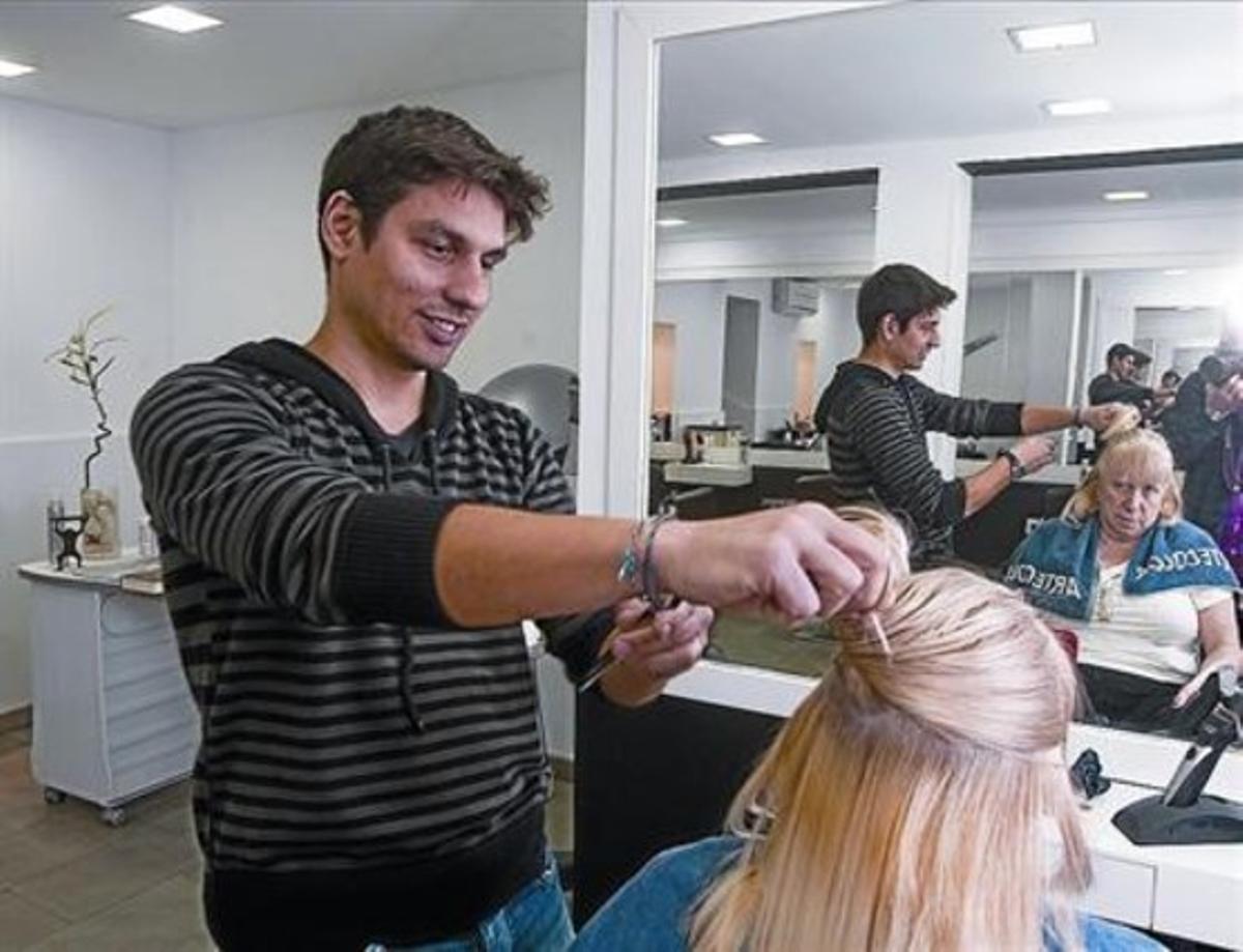 Un trabajador autónomo atiende a una clienta en su peluquería de Barcelona