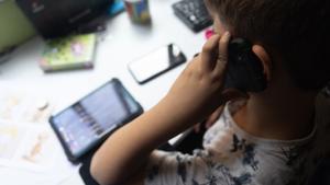 Un niño usa el teléfono móvil y una tablet.