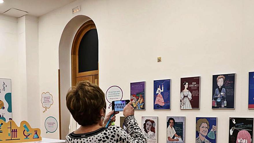 Una mujer fotografía el rincón con la galería de científicas, ayer, en la exposición sobre Margarita Salas en el gijonés Antiguo Instituto. | J. Plaza