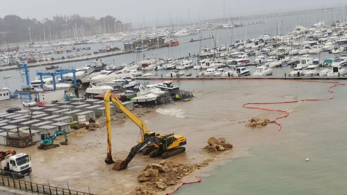 La barrera anticontaminación, rota ayer, y el lodo extendiéndose por la bahía de Baiona.