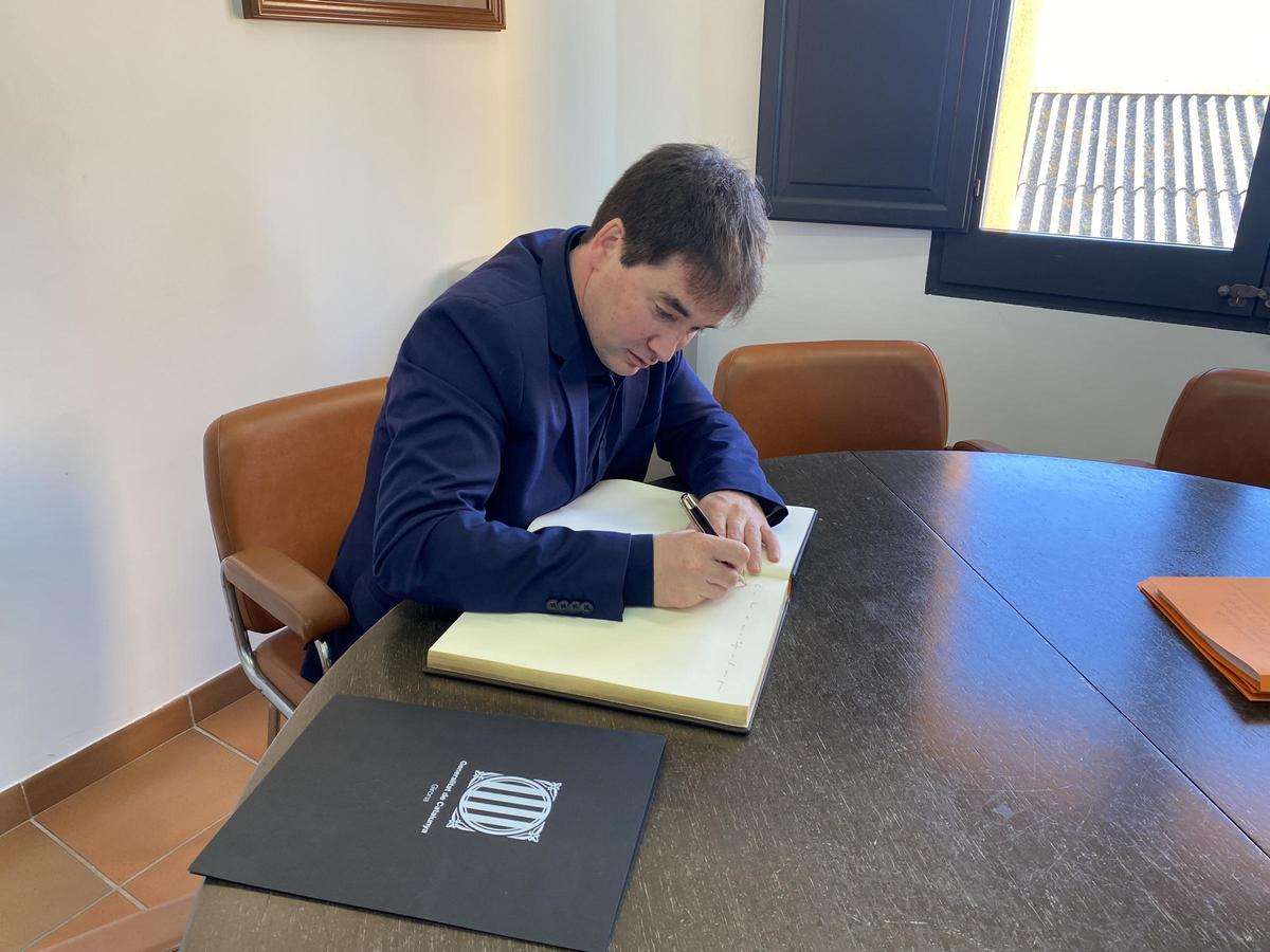El delegat del Govern signant el llibre d'honor d'un dels ajuntaments visitats
