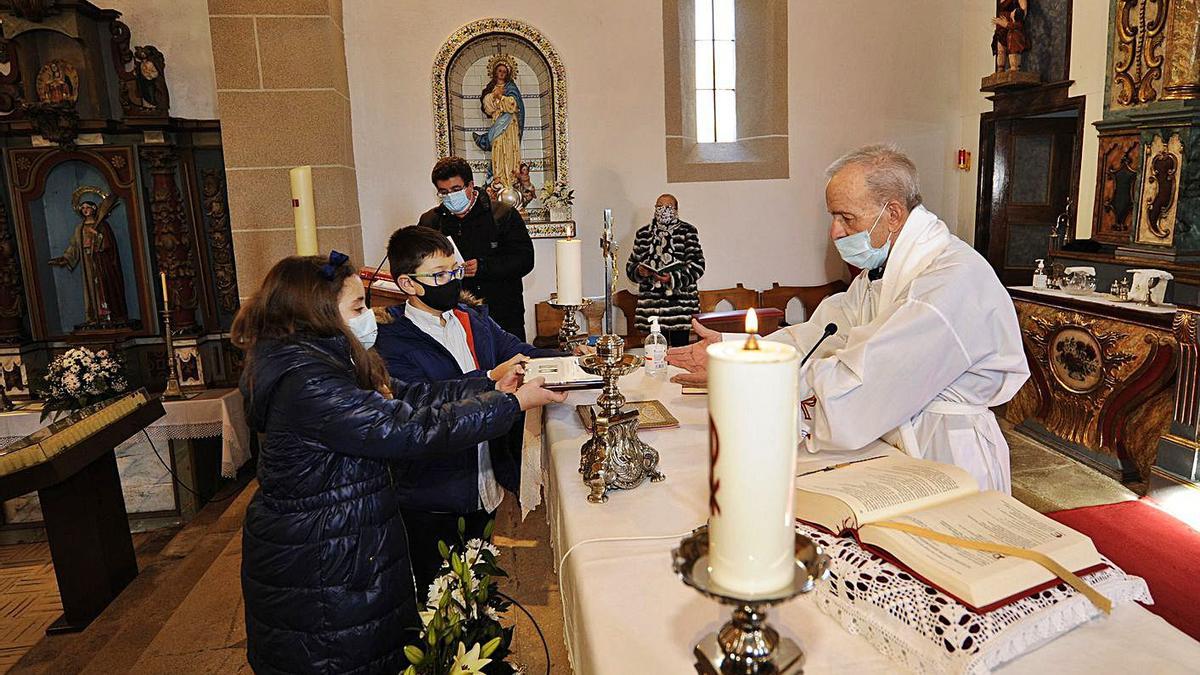 Un niño y una niña entregan la placa al sacerdote, tras la misa dominical.   | // BERNABÉ/JAVIER LALÍN