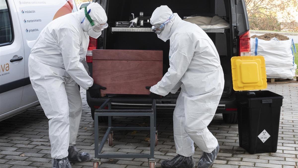 Los funerarios de Mataró trasladan el cuerpo de una persona fallecida por coronavirus dentro del féretro.