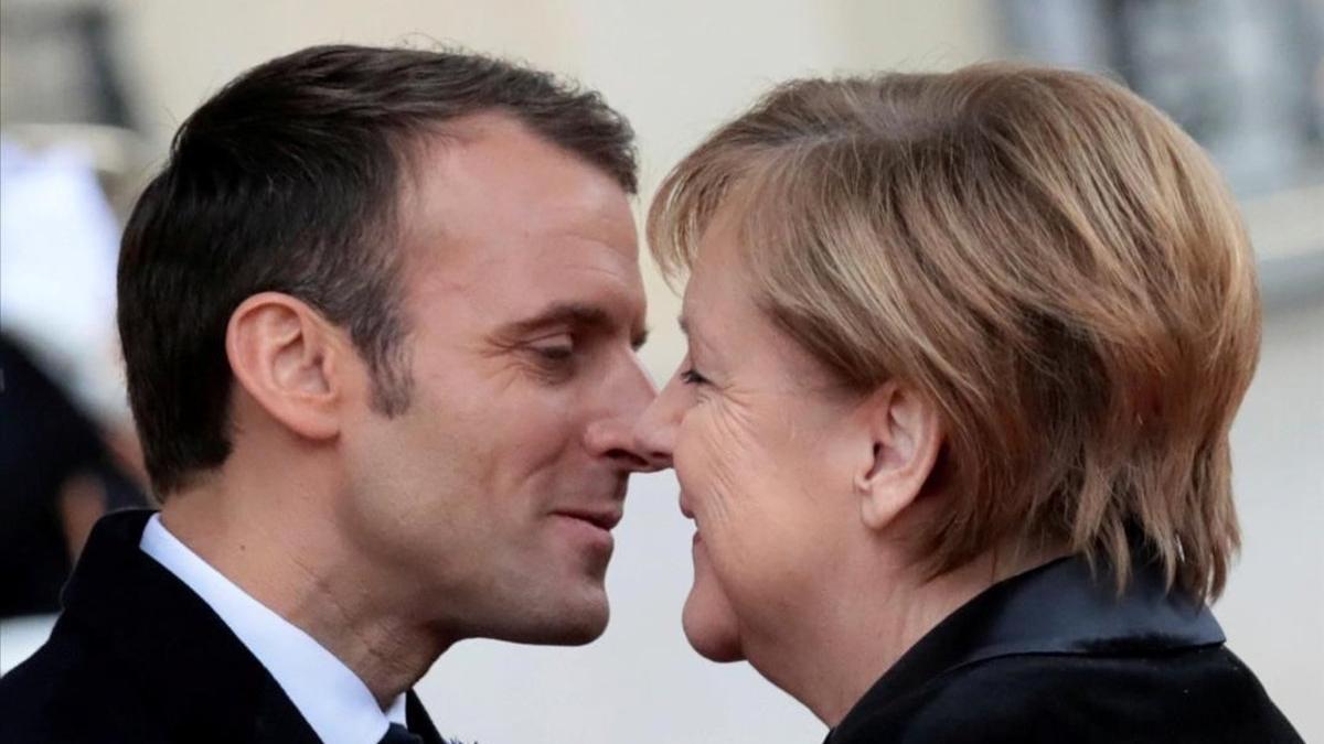 El presidente francés, Emmanuel Macron, y la cancillera alemana, Angela Merkel, se saludan en el Palacio del Elíseo, en París.