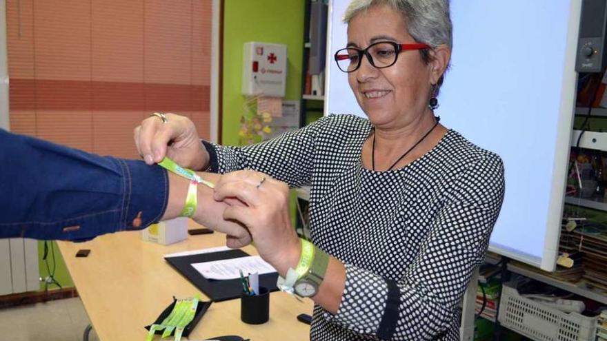 La presidenta de la Asociación de Alzhéimer de Benavente poniendo una pulsera a un colaborador.