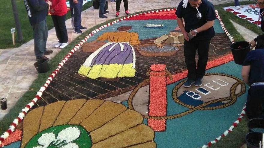 Uno de los alfombristas da los últimos retoques a la alfombra de Bueu. // Alfombras Bueu