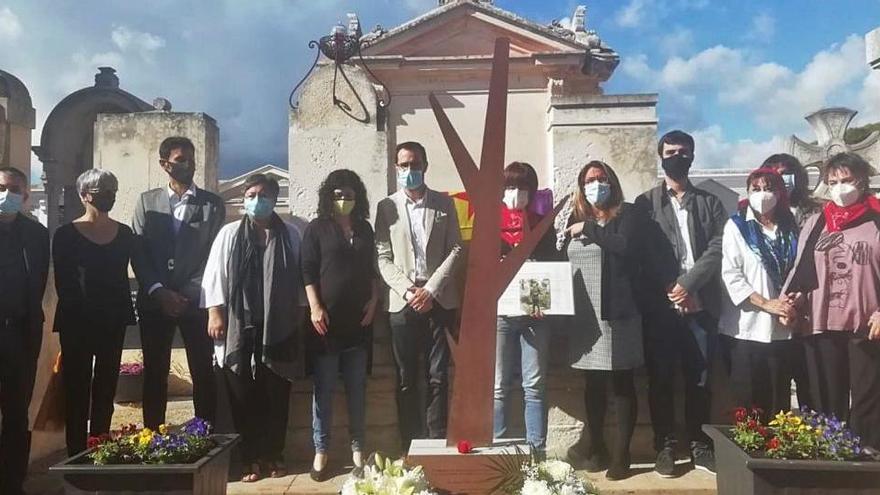 Isabel Cervera, justo detrás del árbol de la memoria, sostiene una fotografía de su tío abuelo Vicente Cervera, junto a otras autoridades en el acto del sábado en el cementerio de Maó.