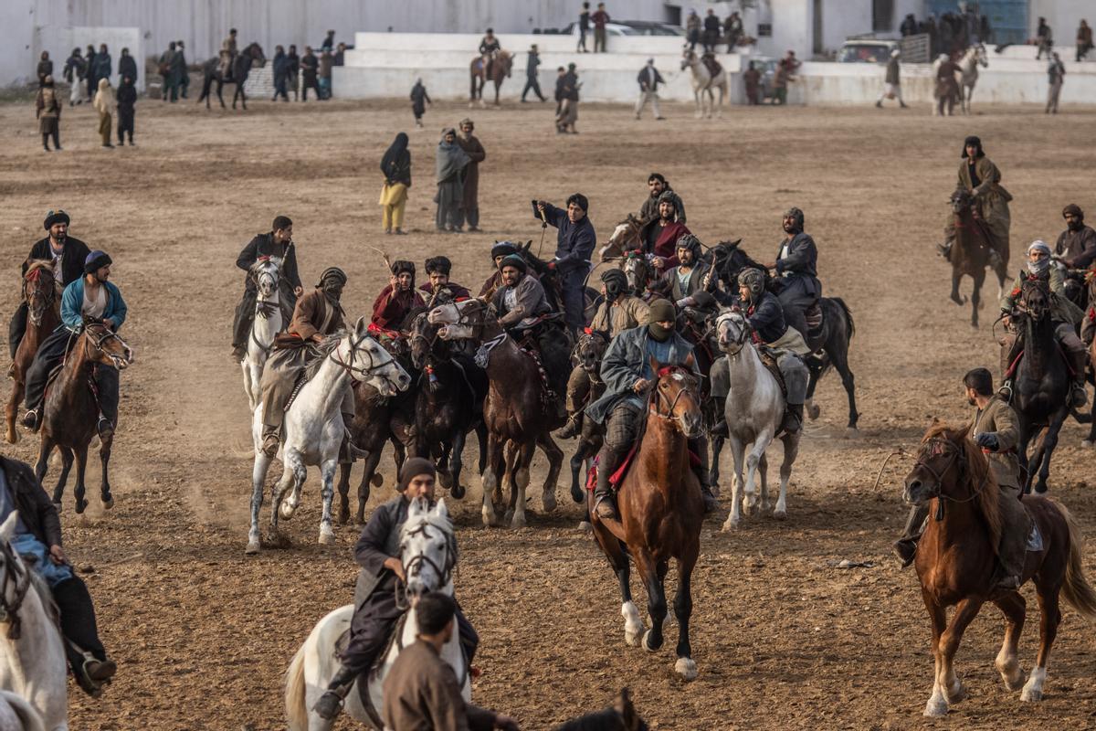 Jinetes afganos compiten en un deporte tradicional de Asia Central, en el que los jugadores montados a caballo intentan colocar una bolsa que se asemeja a un cadáver de cabra en una portería