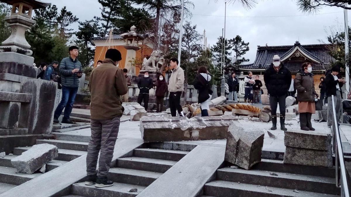 Personas cerca de una puerta torii derrumbada a causa de un terremoto en el Santuario Onohiyoshi en Kanazawa, prefectura de Ishikawa, Japón