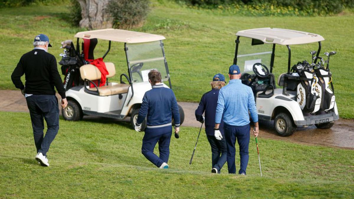 Varios jugadores se acercan en el campo a sus buggies