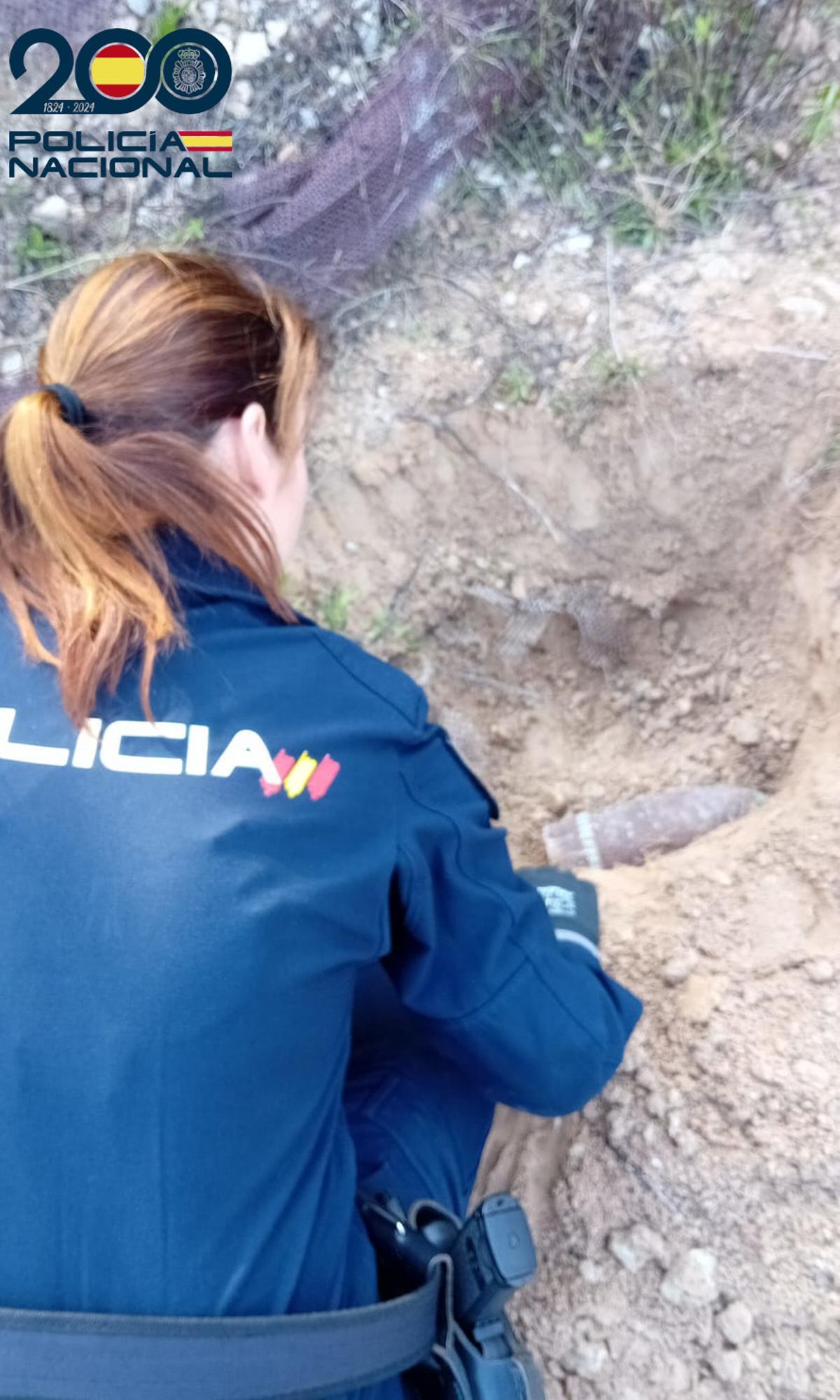 Una agente de Policía examina el proyectil.