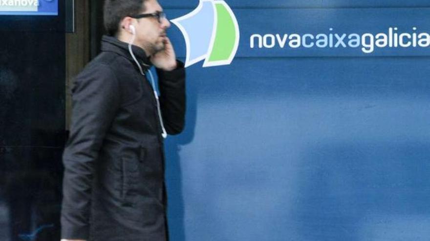 Un hombre pasa ante una oficina de Novacaixagalicia en A Coruña. / fran martínez
