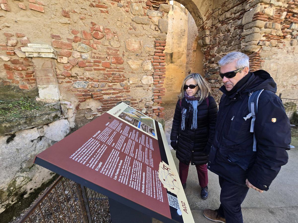 Dos turistas se informan en uno de los paneles de gran tamaño instalado junto a la puerta del Capitel de Badajoz.