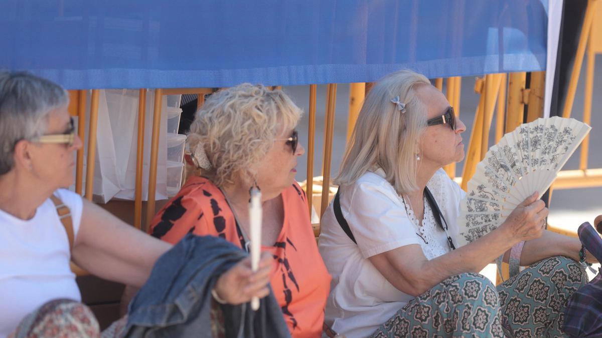 Tres mujeres se protegen del sol a la sombra y con el abanico en València este miércoles.