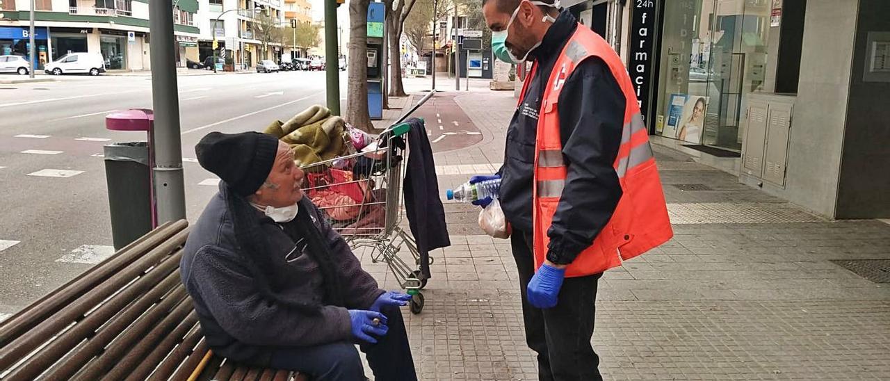 Un voluntario de la Cruz Roja habla con un hombre sin hogar durante el confinamiento.