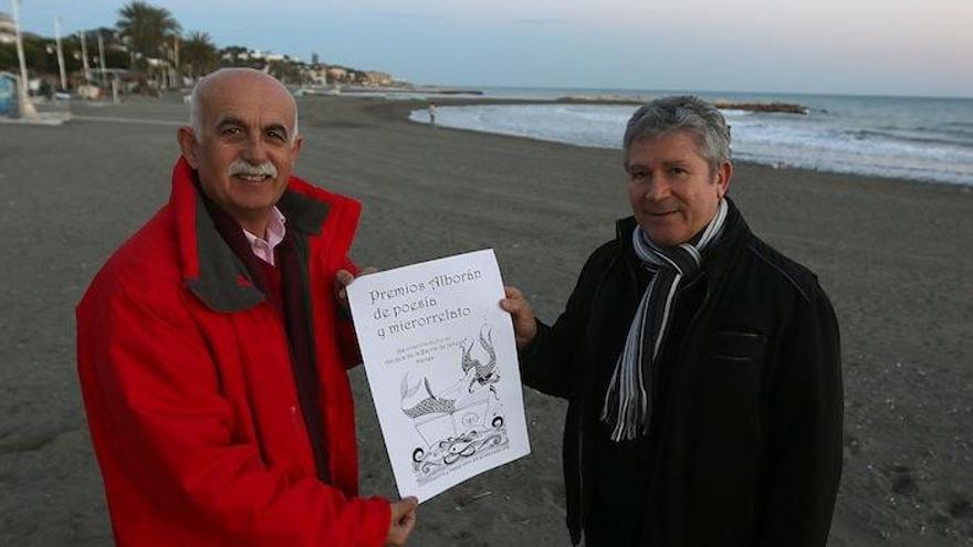 El secretario de la ABJ, Felipe Foj, y el vocal de Literatura, Miguel Moreta, con el cartel del concurso en las playas del Palo.