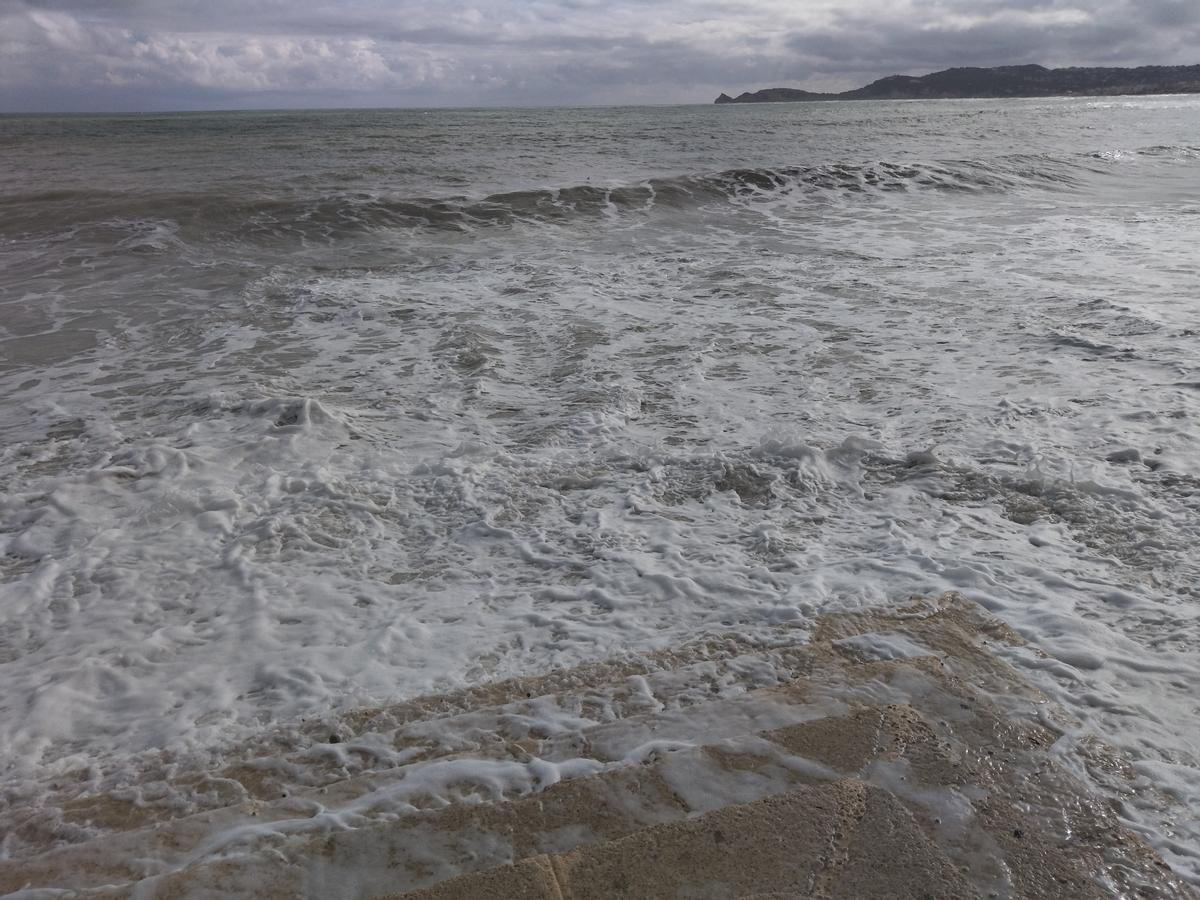 Una ola sube por las escaleras de piedra de la playa de la Grava
