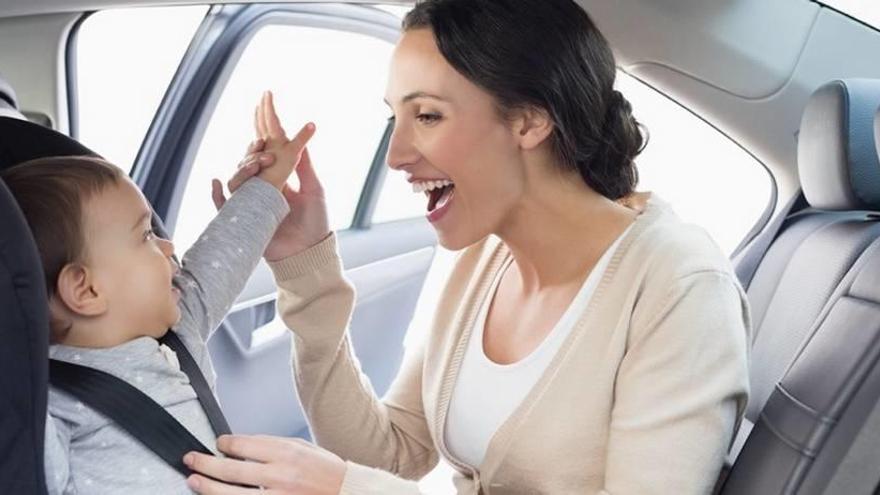 Una madre juega con su bebé dentro de un coche.