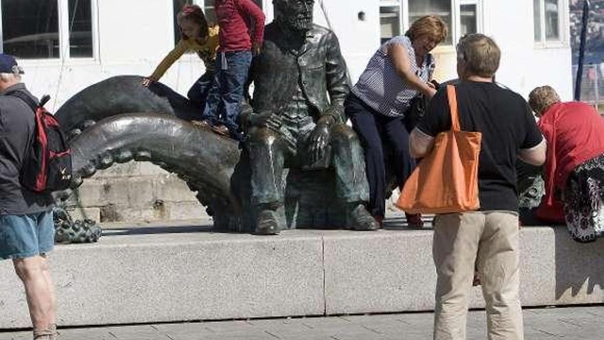 Turistas, fotografiándose en la estatua de Julio Verne en Vigo.  // FdV