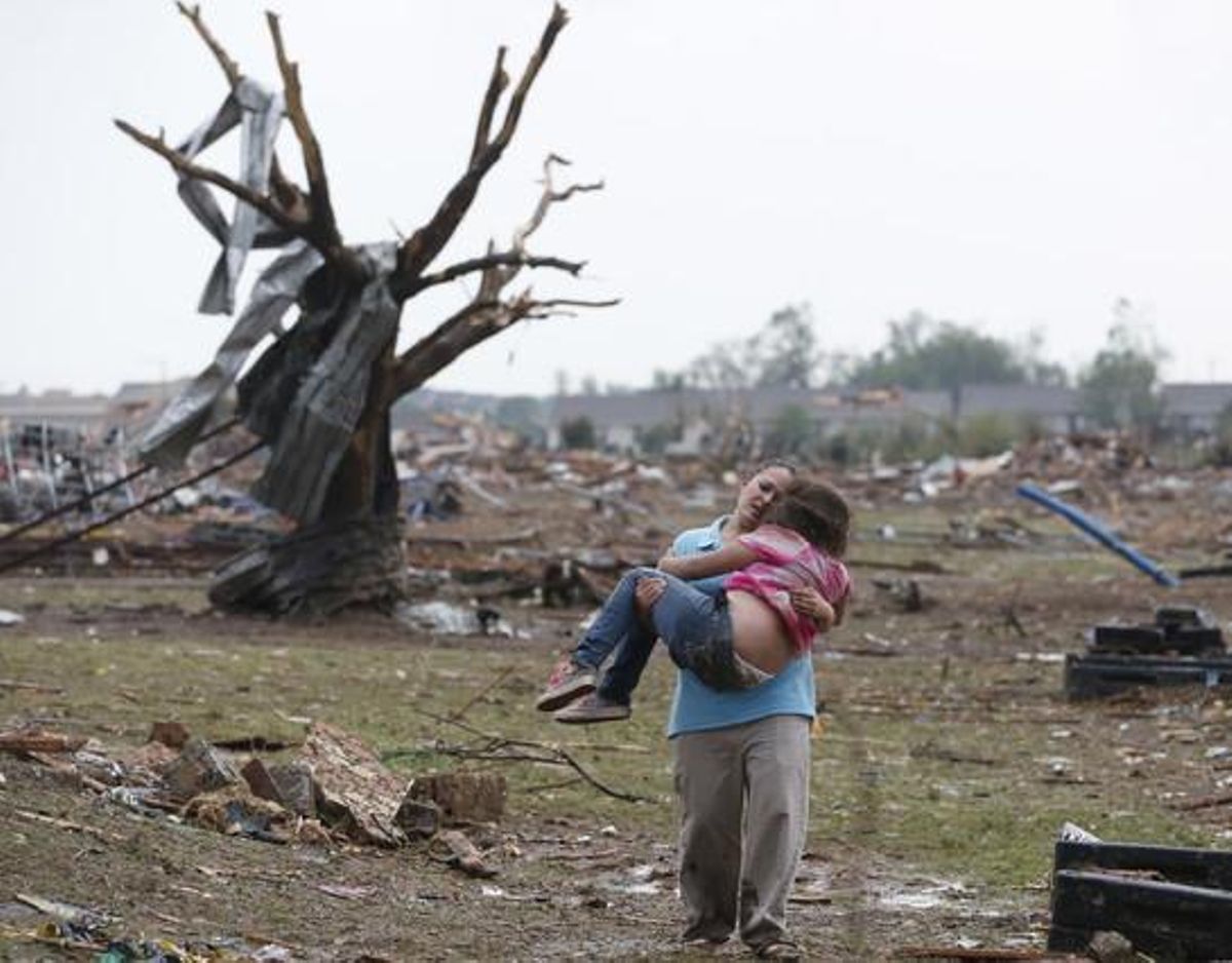 Una dona porta als braços una nena a prop de l’escola devastada pel tornado, aquest dilluns a Oklahoma.