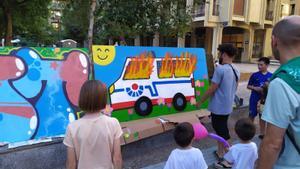 Un grupo de adultos muestra a unos niños en San Sebastián un mural que bromea con el intento de asesinato de unos ertzainas que sufrieron graves quemaduras en Rentería.