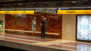 Unos viajeros observan el mapa de la Línea 4 del metro en la parada de Bogatell, en Barcelona.