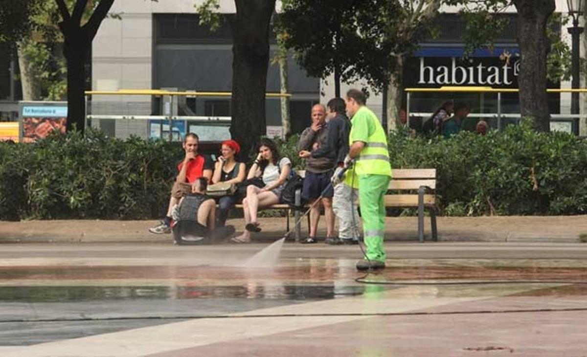 Un treballador del servei de neteja de l’Ajuntament remulla el terra de la plaça de Catalunya l’endemà del desallotjament pacífic dels últims acampats.
