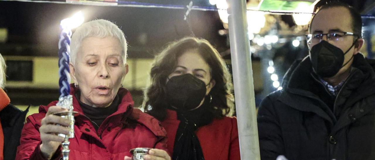 Arriba, Aida Oceransky, Encarnación Vicente y Mario Arias en la plaza del Fontán. Abajo, Jana Oceransky encendiendo una de las velas.| Irma Collín