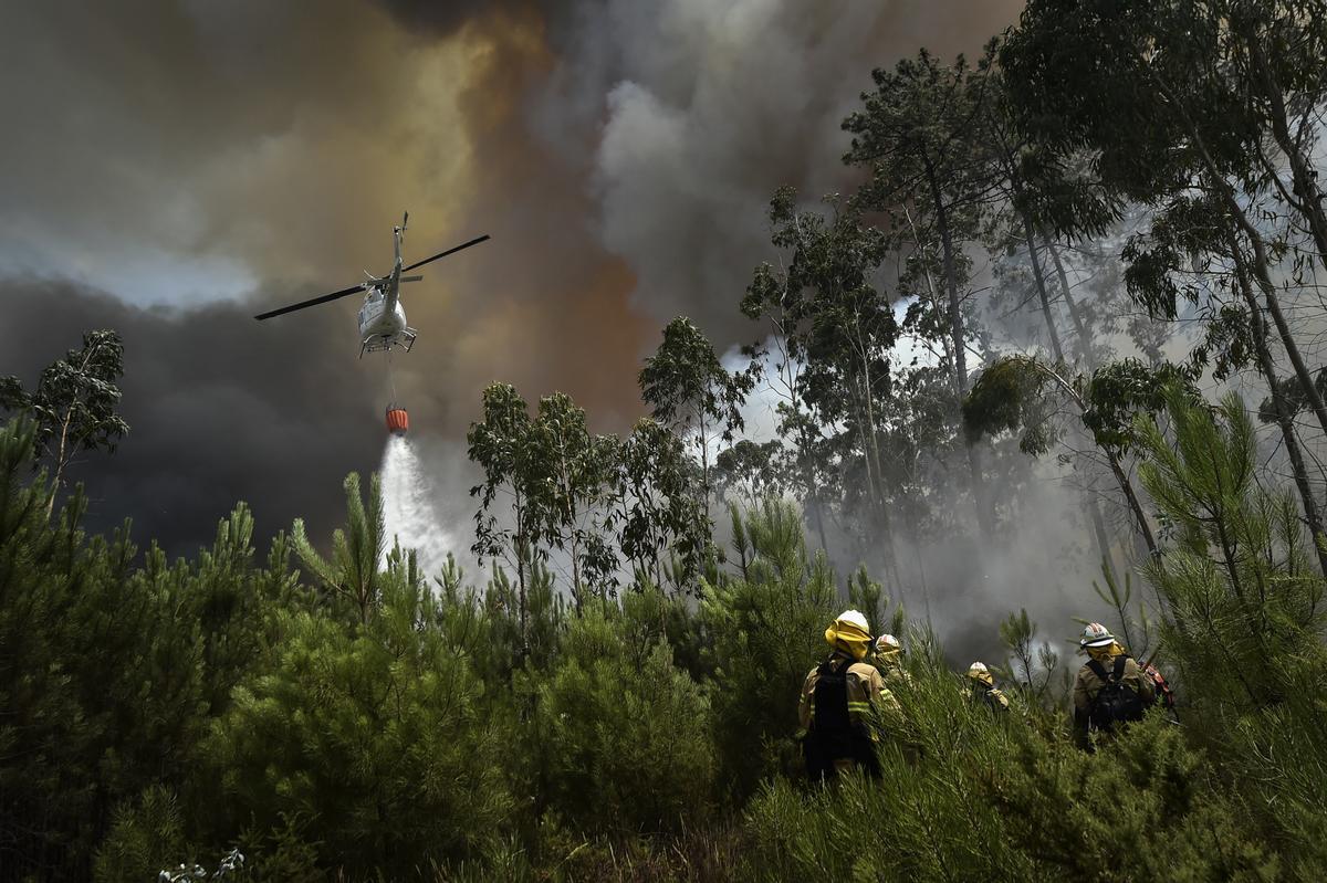 Un helicóptero de extinción de incendios arroja agua sobre el fuego cerca de elementos de la Unidad de Protección y Rescate de Emergencia (UEPS) durante el incendio forestal en el pueblo de Lavradio, Ourem, Portugal, el 13 de julio de 2022. Dieciséis de los 18 distritos de Portugal continental están bajo aviso rojo , la más grave, por el calor, con más de un centenar de comarcas en máximo peligro de incendio rural. (Incendio) EFE/EPA/NUNO ANDRE FERREIRA