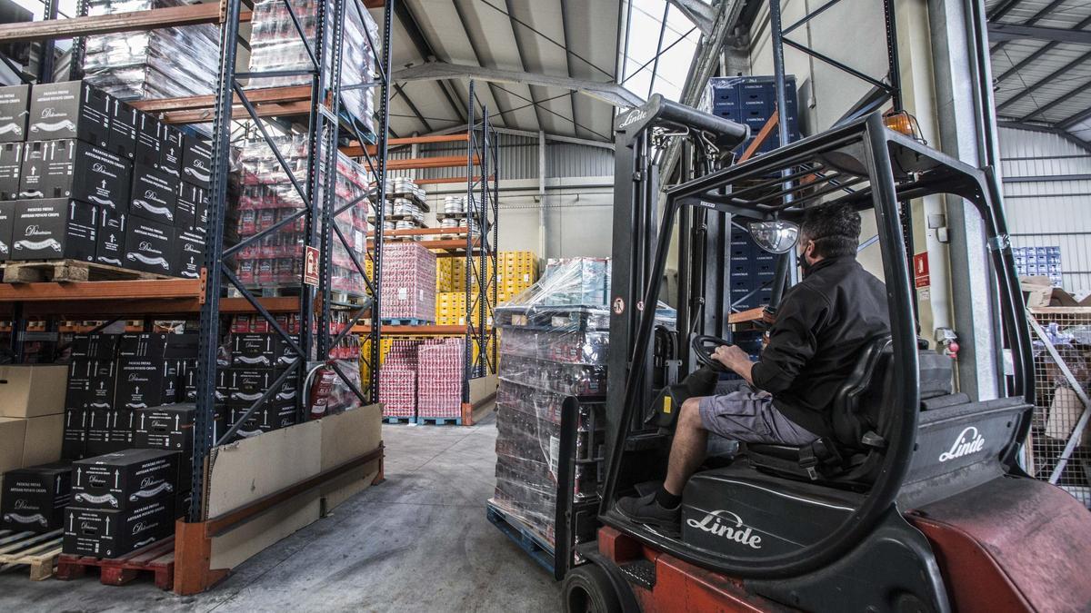 Un trabajador transporta cerveza en los almacenes de la empresa Codile, en Alicante.