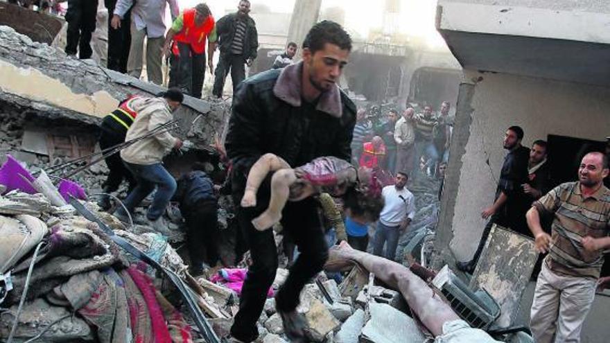 Un hombre traslada el cadáver de un bebé, entre los escombros de un edificio atacado en Gaza.  // Reuters