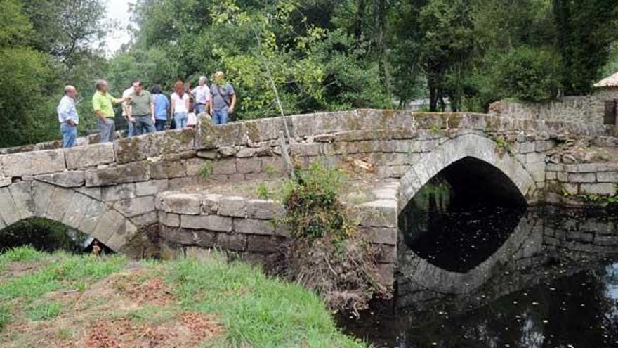 Concejales y vecinos visitan el puente medieval de Bora sobre el río Almofrei, recién restaurado.  // R.V.