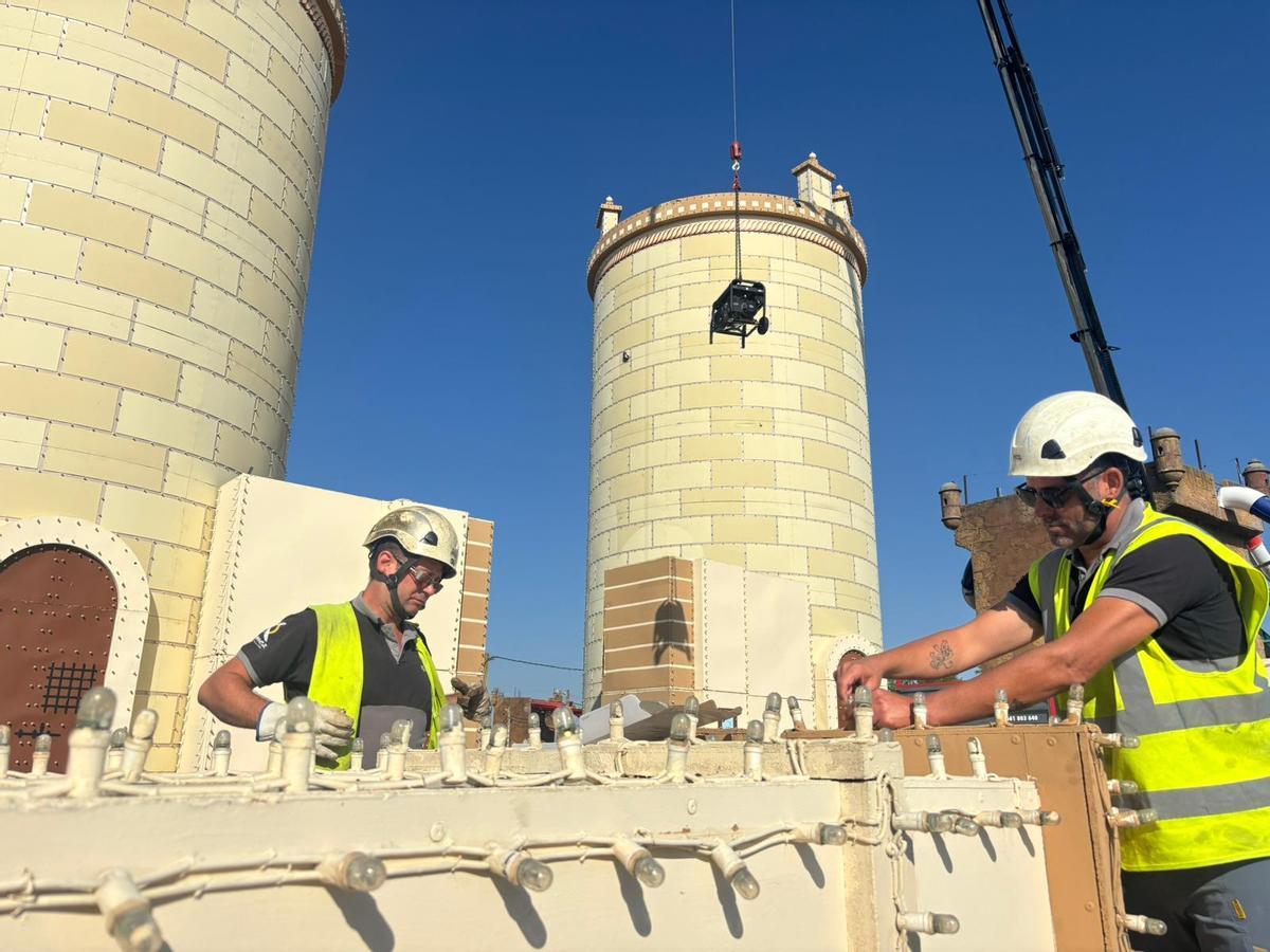 Dos operarios de Grupo Ximénez trabajan en la instalación de la portada de la Feria de San Juan de Badajoz.