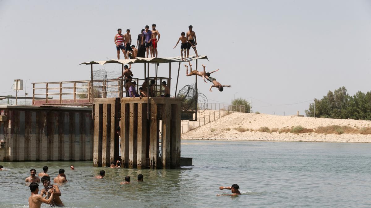 People take a swim and cool off into the Euphrates river, amid increased temperatures, in the holy city of Najaf