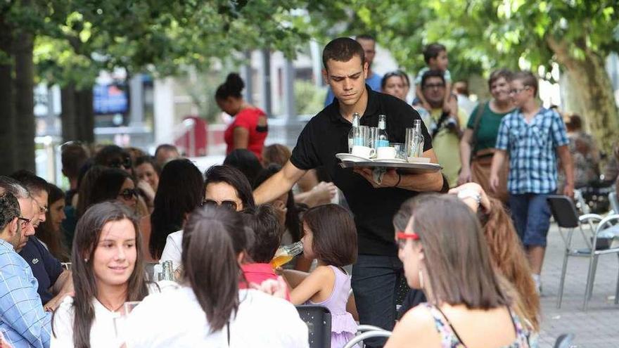 Un camarero sirve a los clientes en la terraza de una cafetería gallega.