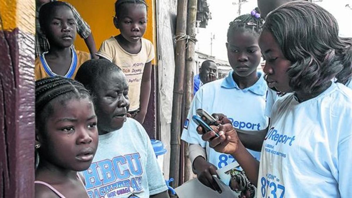 CONTRA EL ÉBOLA. Jóvenes de Liberia leen mensajes contra la epidemia.