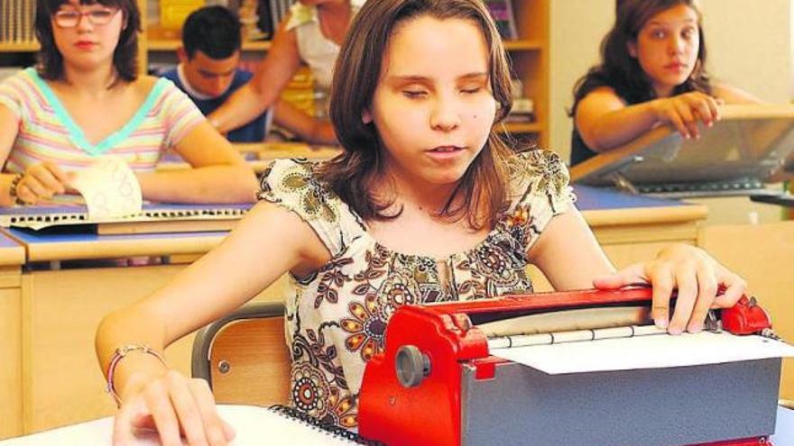 Una alumna ciega pasa apuntes con la máquina de braille. / la opinión